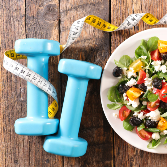 Weights, a measuring tape and a bowl of healthy food